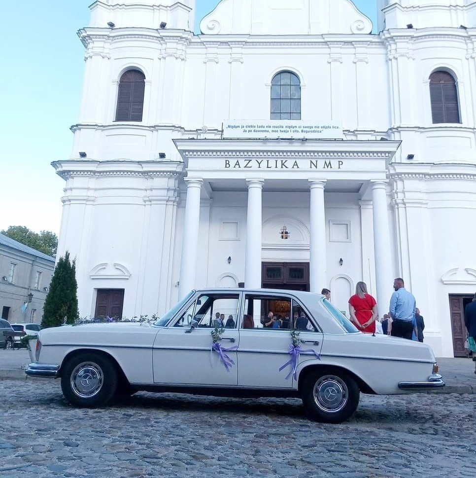 Obraz przedstawiający udekorowanego Mercedesa W108 stojącego przy bazylice